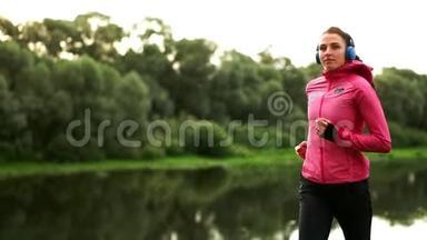 清晨在阳光明媚的黎明时分，在池塘附近的公园里慢跑，女孩正准备去马里亚诺，带领一个健康的人
